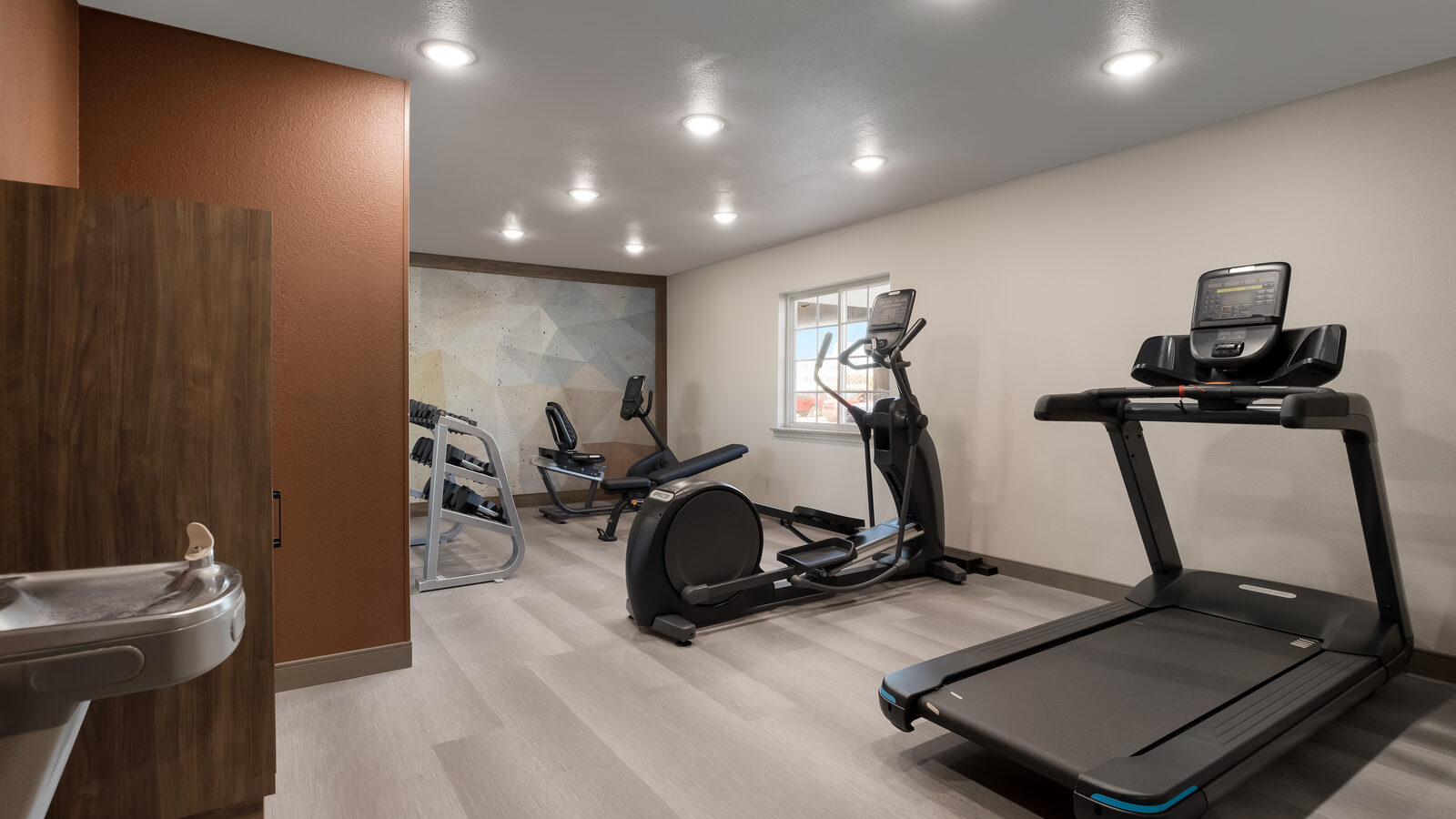 On-site fitness center with cardio equipment, dumbbells, and stretching space